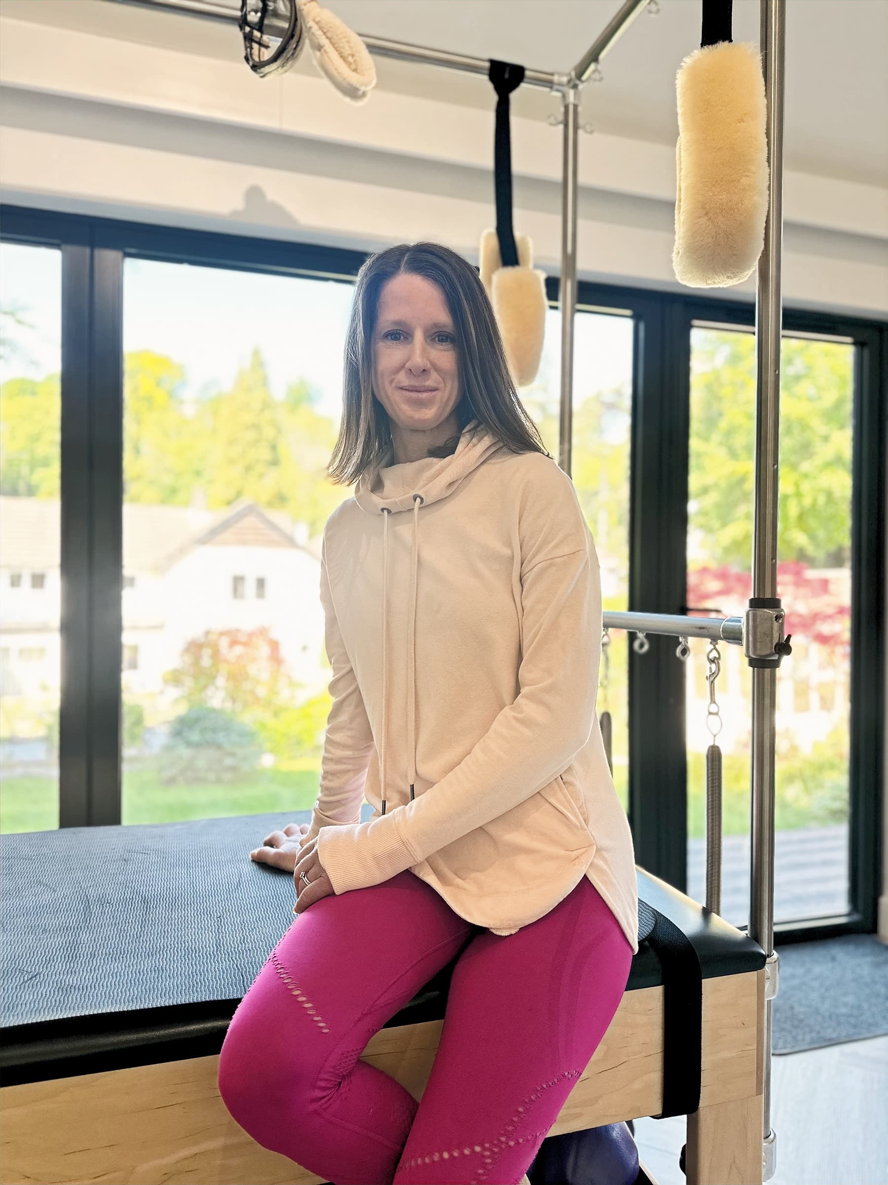 Ali Evans, founder and Pilates teacher, seated on the Cadillac in the Moxie Pilates studio